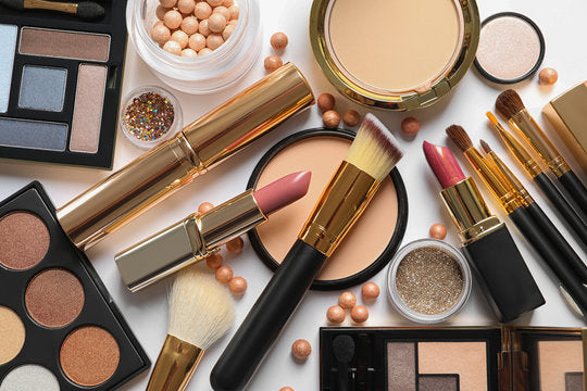 Flat lay of various makeup products including brushes, lipsticks, and eyeshadow palettes.